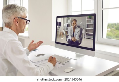 Two Happy Business People Discussing Work In Virtual Online Meeting. Senior Male Executive Manager Or Recruiter Talking To New Young Female Colleague Or Job Seeker Via Video Call On Modern Computer