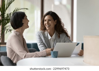 Two happy businesswomen, office employees work in office, laughing, joking during workflow, share creative ideas, solution feel satisfied with corporation, engaged in teamwork. Negotiation, business - Shutterstock ID 2299697473