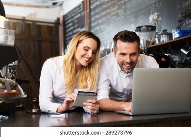 Two happy cafe managers working on laptop - Powered by Shutterstock