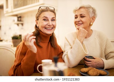 Two happy cheerful middle aged female friends relaxing together at cafeteria, drinking tea, eating cookies, having joyful facial expressions. Aging, leisure, relaxation and friendship concept - Powered by Shutterstock