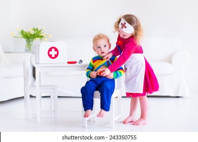 Two happy children, cute toddler girl and adorable baby boy, brother and sister, playing doctor and hospital using stethoscope toy and medical uniform, having fun at home or preschool