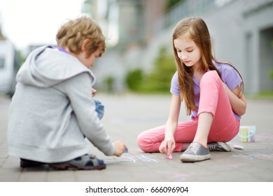 Two Happy Children Drawing With Colorful Chalks On A Sidewalk. Summer Activity For Small Kids. Creative Leisure For Family.