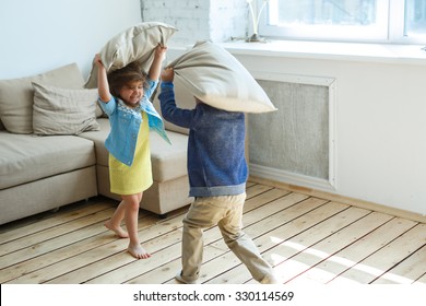 Two Happy Children Is Fighting A Pillows Each Other At Home