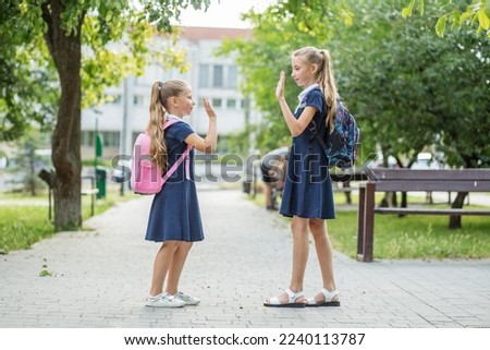 Two happy children met near school with backpacks. Concept of back to school, learning, friendship and childhood.