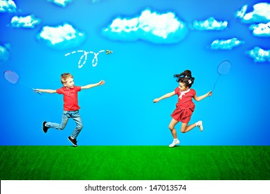 Two happy children playing badminton together over blue sky in a bright summer day.
