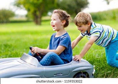 Two Happy Children Playing With Big Old Toy Car In Summer Garden, Outdoor