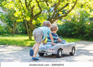 Two happy children playing with big old toy car in summer garden, outdoors. - Powered by Shutterstock