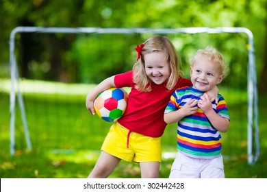 Two Happy Children Playing European Football Outdoors In School Yard. Kids Play Soccer. Active Sport For Preschool Child. Ball Game For Young Kid Team. Boy And Girl Score A Goal In Football Match.