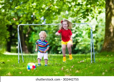 Two Happy Children Playing European Football Outdoors In School Yard. Kids Play Soccer. Active Sport For Preschool Child. Ball Game For Young Kid Team. Boy And Girl Score A Goal In Football Match.