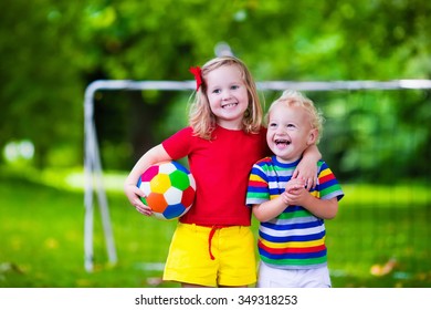 Two Happy Children Playing European Football Outdoors In School Yard. Kids Play Soccer. Active Sport For Preschool Child. Ball Game For Young Kid Team. Boy And Girl Score A Goal In Football Match.