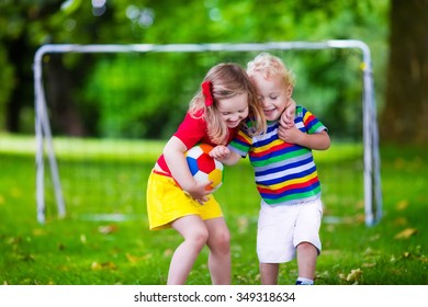 Two Happy Children Playing European Football Outdoors In School Yard. Kids Play Soccer. Active Sport For Preschool Child. Ball Game For Young Kid Team. Boy And Girl Score A Goal In Football Match.