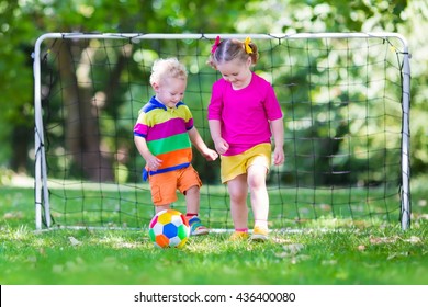 Two Happy Children Playing European Football Outdoors In School Yard. Kids Play Soccer. Active Sport For Preschool Child. Ball Game For Young Kid Team. Boy And Girl Score A Goal In Football Match.