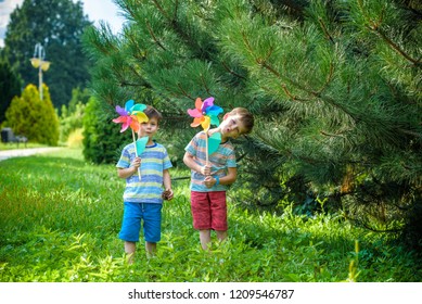 Two Happy Children Playing In Garden With Windmill Pinwheel. Adorable Sibling Brothers Are Best Friends. Cute Kid Boy Smile Spring Or Summer Park. Outdoors Leisure Friendship Family Concept.