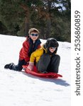 Two happy children playing with a sleigh in the snow on a winter day in the mountains