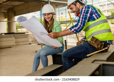 Two Happy Civil Engineer And Maintenance Engineer In Protective Vests And Helmets Working On A Construction Site