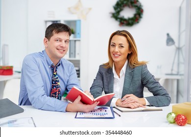 Two happy colleagues looking at camera in office