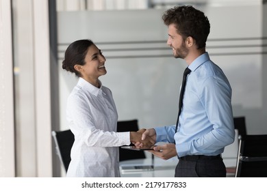 Two happy confident diverse business people shaking hands in office, smiling, laughing, talking. Customer giving handshake to manager, lawyer, ending meeting, negotiation, deal - Shutterstock ID 2179177833