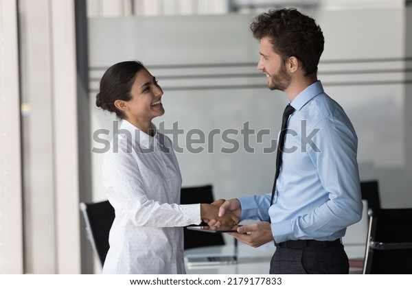 Two happy\
confident diverse business people shaking hands in office, smiling,\
laughing, talking. Customer giving handshake to manager, lawyer,\
ending meeting, negotiation,\
deal