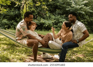 Two happy couples enjoying a leisurely day outdoors, relaxing in a cozy hammock, taking pictures, and sharing joyful moments under the warm summer sun - Powered by Shutterstock