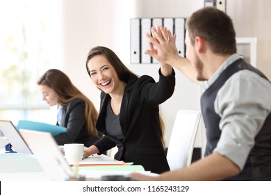 Two happy coworkers celebrating success giving five at office - Shutterstock ID 1165243129