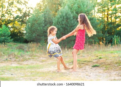 Two Happy cute  little girls embracing and dancing at sunny summer day outdoors