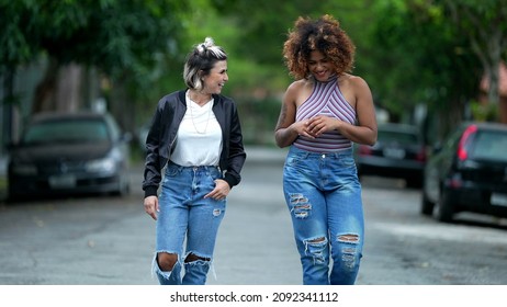 Two Happy Diverse Friends Walking Together Outside In Street Laughing And Smiling Together