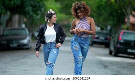 Two Happy Diverse Friends Walking Together Outside In Street Laughing And Smiling Together