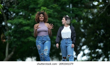 Two Happy Diverse Friends Walking Together Outside In Street Laughing And Smiling Together