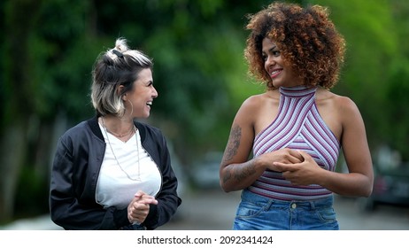 Two Happy Diverse Friends Walking Together Outside In Street Laughing And Smiling Together