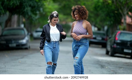 Two Happy Diverse Friends Walking Together Outside In Street Laughing And Smiling Together