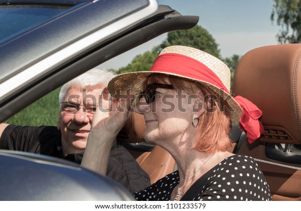 Two happy elderly people in\
car