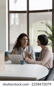 Two happy engaged business professionals women brainstorming on online project at laptop, speaking, discussing creative ideas, plan, strategy, task, chatting at work desk in office - Shutterstock ID 2258472079