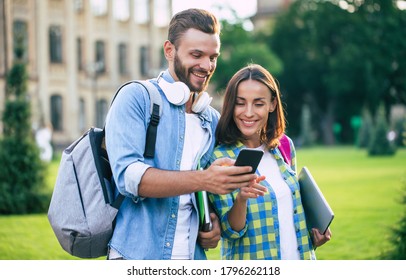 Two happy and excited student friends with backpacks and smartphone are have conversation and walking outdoors. Beautiful couple after lessons in university - Powered by Shutterstock