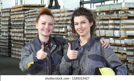 Two happy female factory workers embracing showing thumbs up at the storage - Powered by Shutterstock