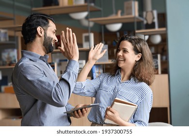 Two happy friendly diverse professionals, teacher and student giving high five standing in office celebrating success, good cooperation result, partnership teamwork and team motivation in office work. - Powered by Shutterstock