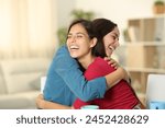 Two happy friends are hugging and laughing at home