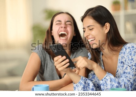 Similar – Two women laughing looking at their smart phone