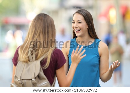 Two happy friends meeting and greeting on the street with a blurred background