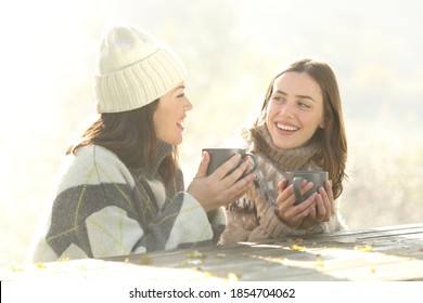 Two happy friends talking at breakfast sitting in winter foggy morning outdoors - Powered by Shutterstock