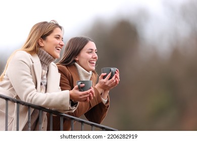 Two happy friends talking and drinking in a balcony in winter - Shutterstock ID 2206282919