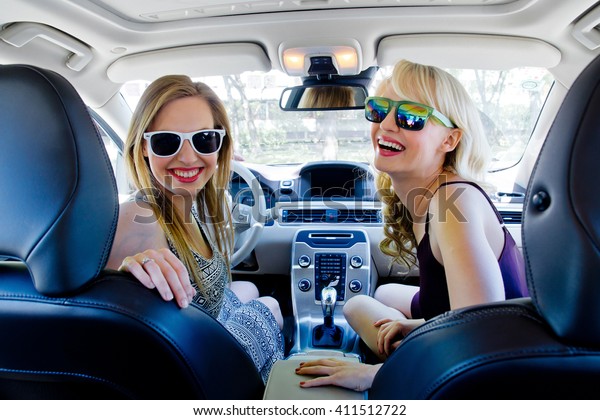 two happy girl\
friends in the car having\
fun