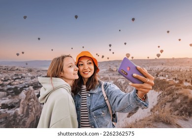 Two happy girl friends taking selfie photos on smartphone in Cappadocia, Turkey. Travel and social media concept - Powered by Shutterstock