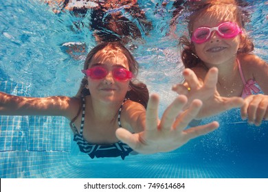 Two Happy Girls In Goggles Swimming Under Water