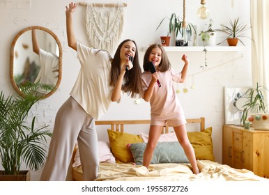 Two Happy Girls, Overjoyed Younger And Older Sister Singing With Hairbrush, Looking At Camera And Smiling While Spending Time Together At Home, Mom And Cute Little Daughter Having Fun In Bedroom