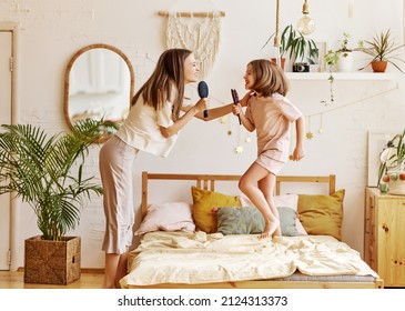 Two Happy Girls, Overjoyed Younger And Older Sister Singing With Hairbrush, Looking At Each Other And Smiling While Spending Time Together At Home, Mom And Cute Little Daughter Having Fun In Bedroom