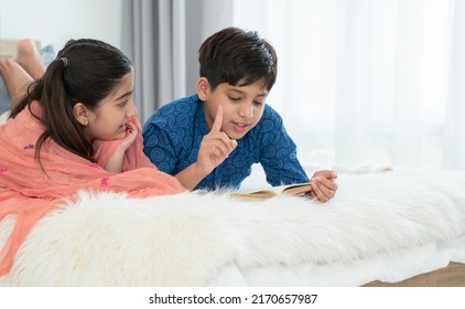 Two happy Indian brother and sister in traditional clothing lying on bed and reading book, having fun together at home. Education, Siblings relationship concept - Shutterstock ID 2170657987