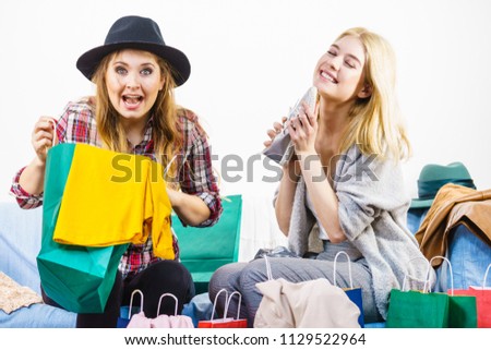 Two happy joyful women having fun after shopping, picking outfit in closet. Female friends fooling around.