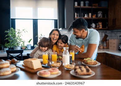 Two happy kids, boy and girl enjoying eating breakfast with parents. Smiling beautiful mother laughing and having fun with her kids and husband during breakfast at home. - Powered by Shutterstock