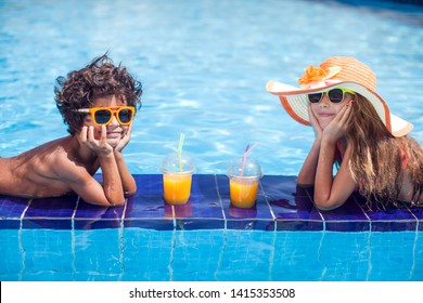 Two Happy Kids Girl And Boy Drink Juice In The Pool And Have Fun. Children And Summer Concept