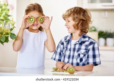 Two Happy Kids Having Fun With Kiwi In A Kitchen